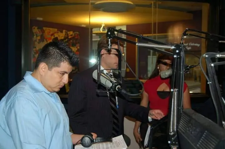 Cabina de radio con locutores frente a los micrófonos durante una transmisión